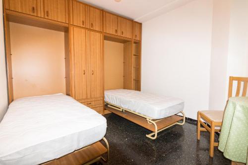 a bedroom with two beds and a chair at Biescas Doctor Fleming in Biescas