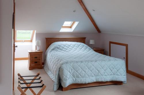 a bedroom with a bed with a blue comforter and a window at Creeghduff Lodge in Downpatrick
