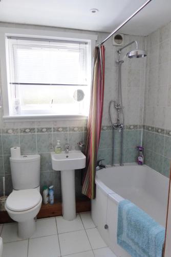 a bathroom with a toilet and a tub and a sink at Tom Morris Drive in Fife