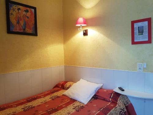 a room with a bed and a lamp and a sink at Hôtel du Centre in Lourdes
