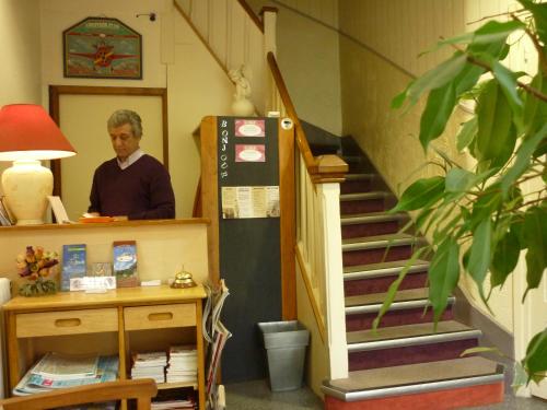 a man standing in a room next to a staircase at Hôtel du Centre in Lourdes