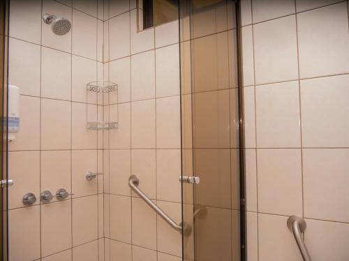 a shower in a bathroom with white tiles at Hotel Bamboo Aeropuerto in Alajuela City