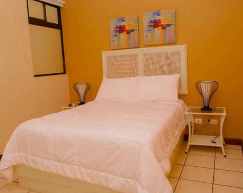 a bedroom with a white bed and a yellow wall at Hotel Bamboo Aeropuerto in Alajuela City