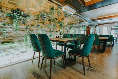 a dining room with a table and green chairs at Lostrita - Pastravarie, Hotel & SPA in Baia Mare