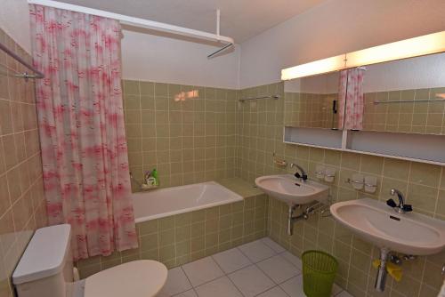 a bathroom with two sinks and a bath tub at Monami Apartments Klosters, Ferienhaus Jörgenberg in Klosters