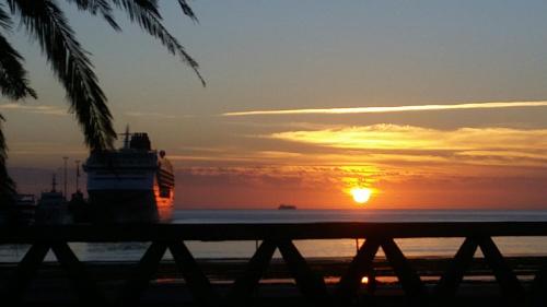 a sunset over the ocean with a bench in the foreground at Alem in Puerto Madryn