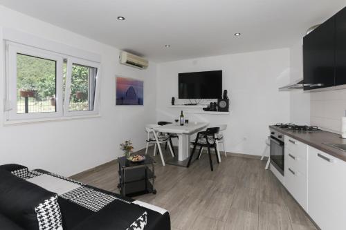 a white living room with a kitchen and a table at Holiday Home Rupotina with a large yard, pool and a beautiful view in Solin