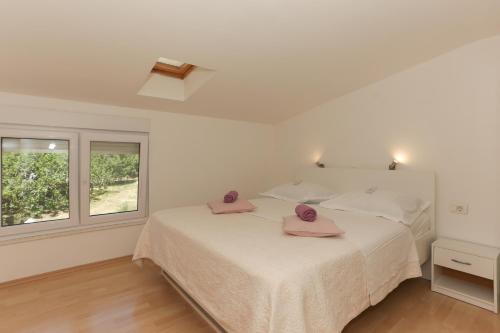 a white bedroom with a bed with pink towels on it at Holiday Home Rupotina with a large yard, pool and a beautiful view in Solin
