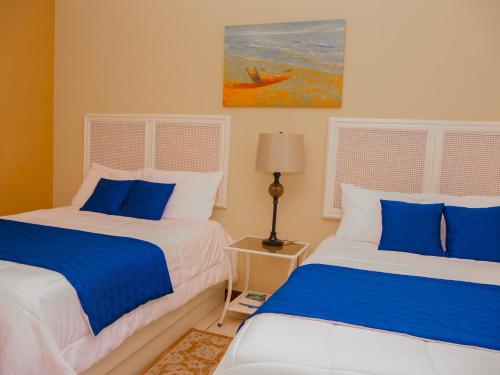 two beds in a room with blue and white at Hotel Bamboo Aeropuerto in Alajuela City