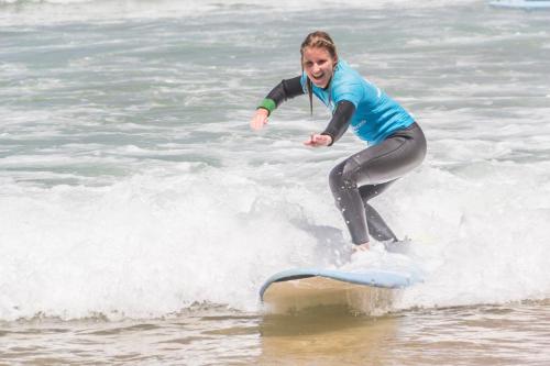 a woman riding a wave on a surfboard in the ocean at Wavesensations - Sagres Surf House in Sagres