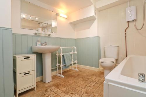 a bathroom with a sink and a toilet and a tub at TOWN CENTRE apartment with parking in Padstow