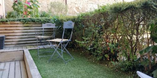 2 sillas y una mesa en un jardín en LE GARDEN CENTRAL STUDIO, en Dinan