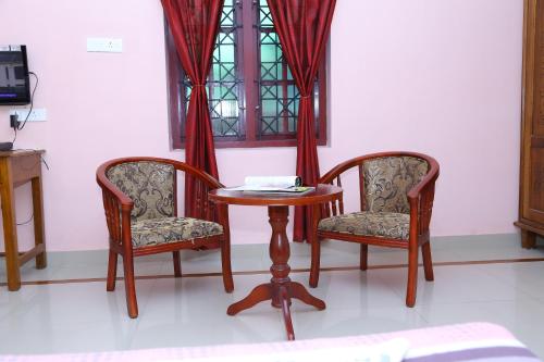 mesa, 2 sillas, mesa y ventana en princess inn royal, en Trivandrum