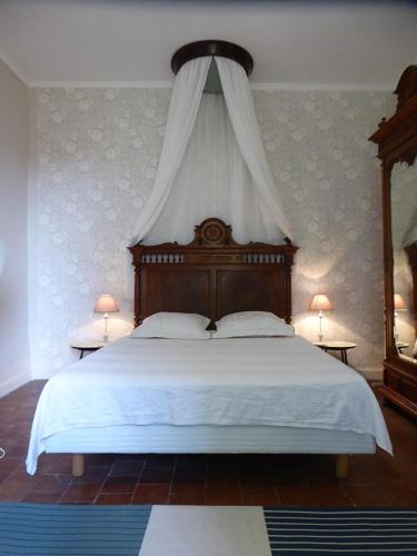 - une chambre avec un grand lit blanc à baldaquin dans l'établissement Domaine de Lamartine, à Pont-Saint-Esprit