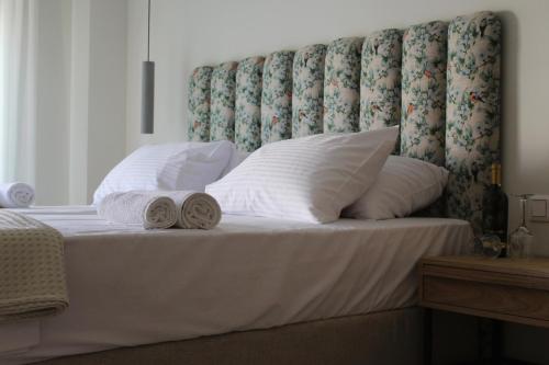 a bed with pillows and towels on it with a headboard at Thetis Boutique Apartments in Neos Marmaras