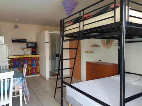 a room with two bunk beds and a kitchen at Studio Pitaya in Les Trois-Îlets