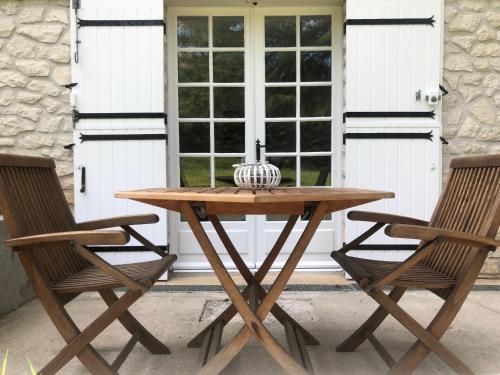 - une table en bois et 2 chaises sur la terrasse dans l'établissement MAISON BLANCHE, à Saint-Laurent-sur-Manoire