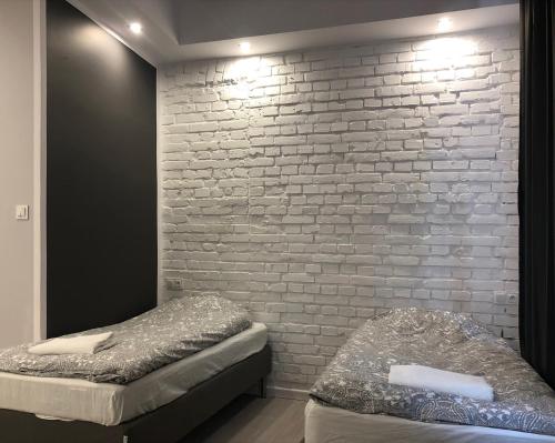 two beds in a room with a brick wall at Aparthotel 11 in Kwidzyn