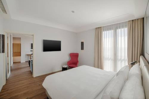 a hotel room with a white bed and a red chair at Radisson Blu Hotel Milan in Milan