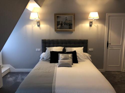 ein Schlafzimmer mit einem großen Bett mit schwarzen und weißen Kissen in der Unterkunft MAISON BLANCHE in Saint-Laurent-sur-Manoire
