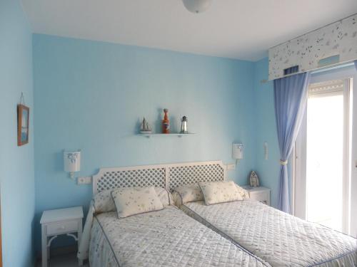 a bedroom with a bed with blue walls and a window at Dúplex La Manga del Mar Menor Pedruchillo in La Manga del Mar Menor