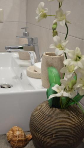 a bathroom with a vase with white flowers in it at ZI DIMA APARTMENTS in Giardini Naxos