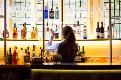 a woman sitting at a bar with bottles of wine at The Painswick in Painswick
