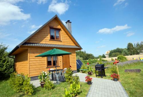 a small wooden house with a patio and a table at Domek Twórczy Kąt in Święta Katarzyna