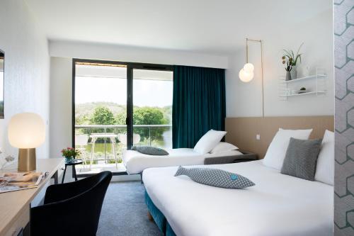 a hotel room with two beds and a desk at Best Western Plus Hotel les Rives du Ter in Larmor-Plage