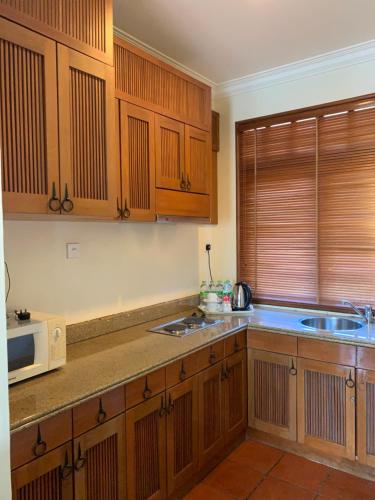 a kitchen with wooden cabinets and a microwave at SEA VILLA LANGKAWI LAGOON in Pantai Cenang
