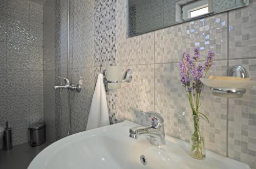 baño con lavabo y jarrón de flores púrpuras en Bistra Guest Rooms, en Kranevo