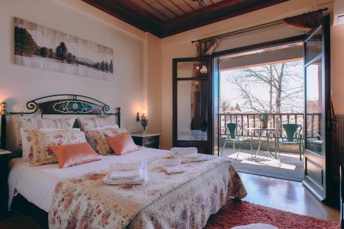 a bedroom with a large bed and a balcony at Etheres Tzoumerkon Mountain Resort in Katarr&aacute;ktis