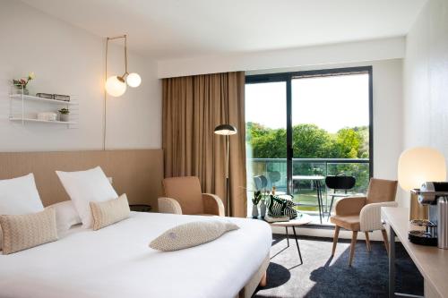 Cette chambre comprend un lit et une grande fenêtre. dans l'établissement Best Western Plus Hotel les Rives du Ter, à Larmor-Plage