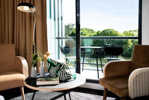 a living room with two chairs and a table with a pillow at Best Western Plus Hotel les Rives du Ter in Larmor-Plage