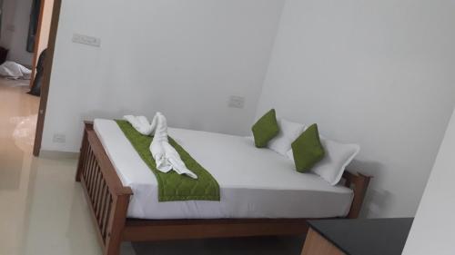 a bed with green and white pillows on it at GOLDEN VILLA in Cochin