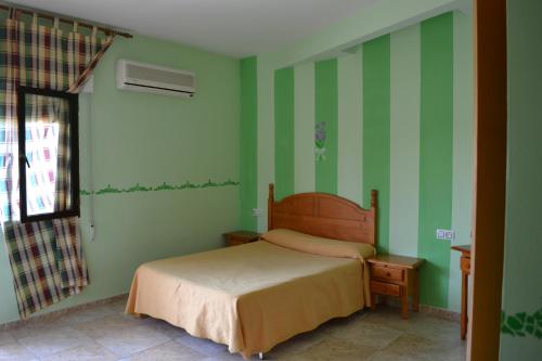 a bedroom with green striped walls and a bed at Hostal Vadillo in Losar de la Vera