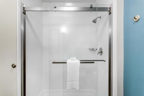 d'une douche avec une porte en verre et une serviette. dans l'établissement Sleep Inn & Suites Monroe - Woodbury, à Monroe