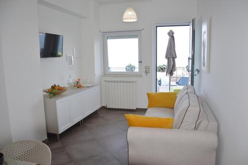 ein Wohnzimmer mit einem weißen Sofa und einem Fenster in der Unterkunft ZI DIMA APARTMENTS in Giardini-Naxos