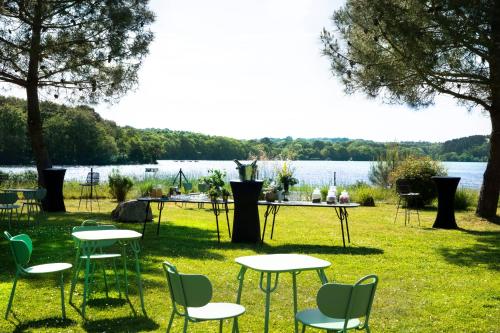 a group of tables and chairs in front of a lake at Best Western Plus Hotel les Rives du Ter in Larmor-Plage