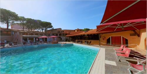 een groot zwembad met stoelen en een gebouw bij Club Esse Cala Bitta in Baja Sardinia
