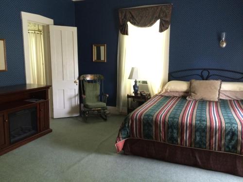 a bedroom with a bed and a window and a chair at Antique Mansion B & B in Rutland