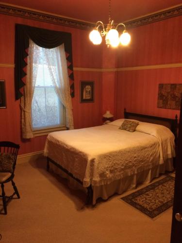 a bedroom with a bed and a window and a chandelier at Antique Mansion B & B in Rutland