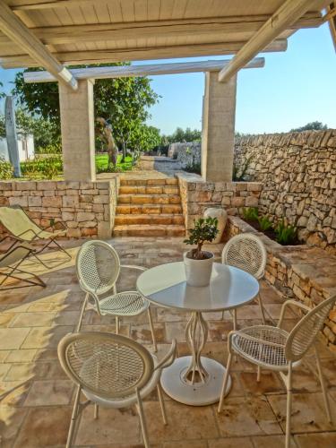 a patio with a table and chairs and a stone wall at Masseria Rosa Trulli Relais in Alberobello