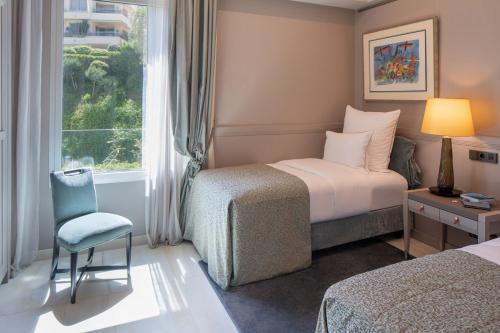 Habitación de hotel con cama, silla y ventana en Alàbriga Hotel & Home Suites GL, en S'Agaró