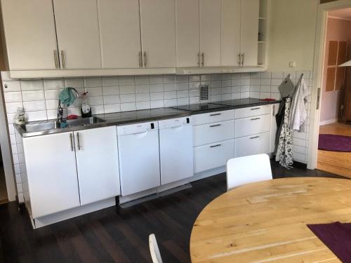 a kitchen with white cabinets and a wooden table at Bergåsa bed & kitchen Drängsered in Torup