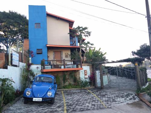 een blauwe auto geparkeerd voor een huis bij Pousada Natureza e Arte in Cunha