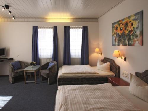 a hotel room with two beds and a chair at Hotel Köhler in Braunschweig