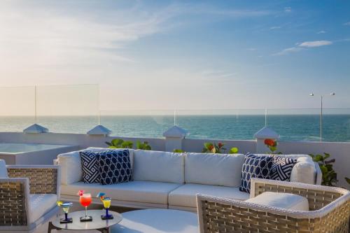 a patio with a couch and chairs and the ocean at Casa La Merced by Mustique in Cartagena de Indias