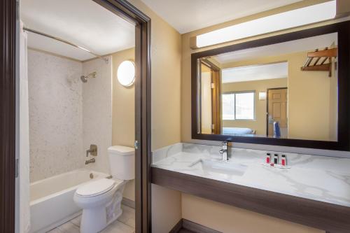 a bathroom with a sink and a toilet and a mirror at Days Inn Merced / Yosemite Area in Merced