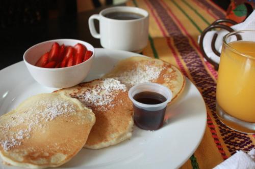 um prato com duas panquecas e uma taça de morangos em Hotel Andoria em San Salvador